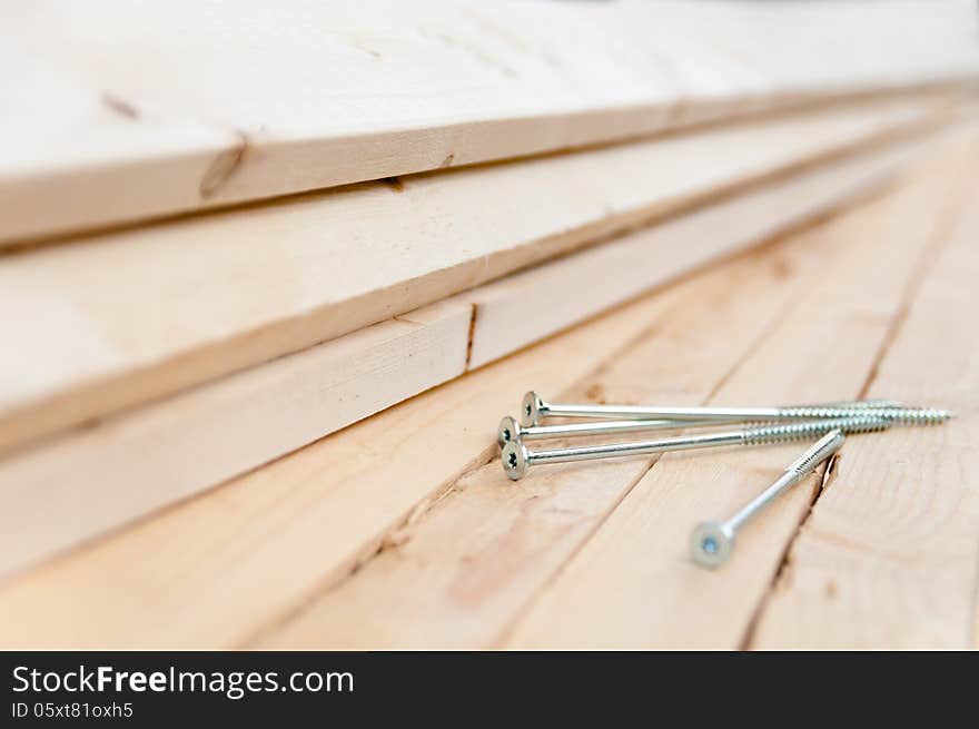 Long screws lie on the wooden boards close-up