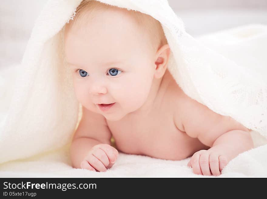 Smiling baby looking at camera under a white blanket/towel. Smiling baby looking at camera under a white blanket/towel