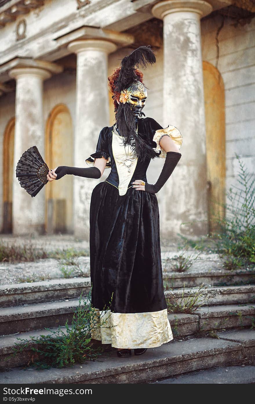 Portrait of red-haired woman holding a mask shot against the background of columns. Portrait of red-haired woman holding a mask shot against the background of columns