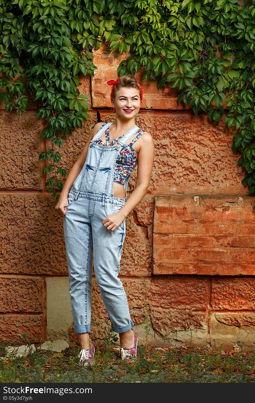 Beautiful pin-up girl in denim overalls and a T-shirt outdoors