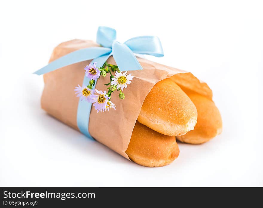 Fresh buns in paper bag decorated with ribbon and flowers isolated on white