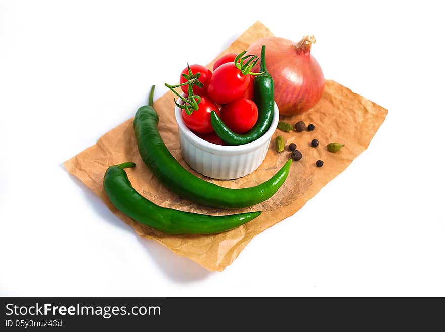 Tomato and chili peppers in white cup isolated on white