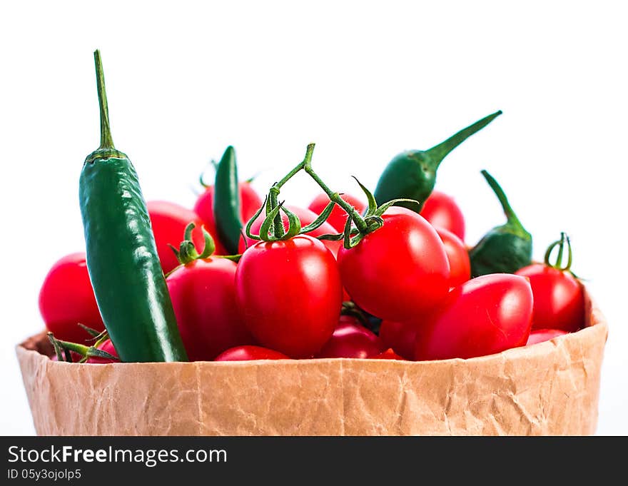 Tomatoes and chili peppers in paper bagisolated on white. Tomatoes and chili peppers in paper bagisolated on white