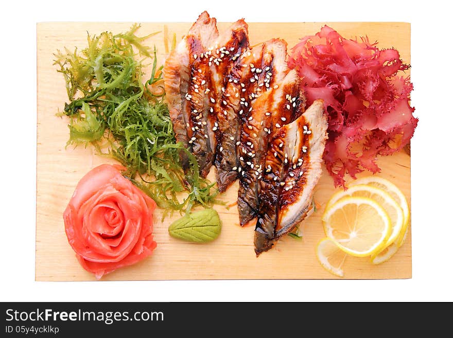 Sashimi unagi with slices of eel, lemon lobules, ginger, wasabi, red and green algae on rectangular board isolated on a white background. Top view. Sashimi unagi with slices of eel, lemon lobules, ginger, wasabi, red and green algae on rectangular board isolated on a white background. Top view.