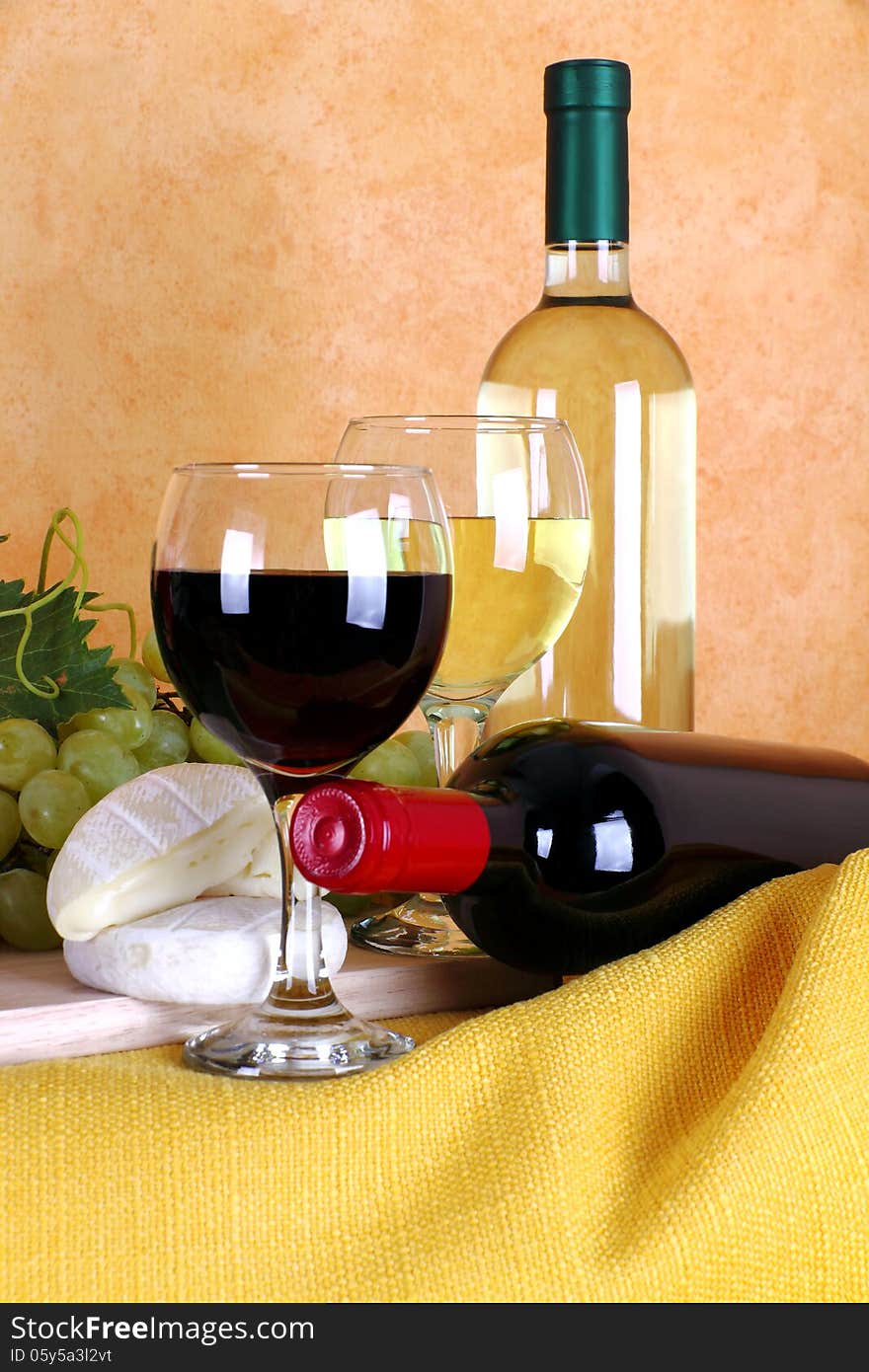 Red wine and white wine with glass in the foreground alongside cheese and grapes. Red wine and white wine with glass in the foreground alongside cheese and grapes