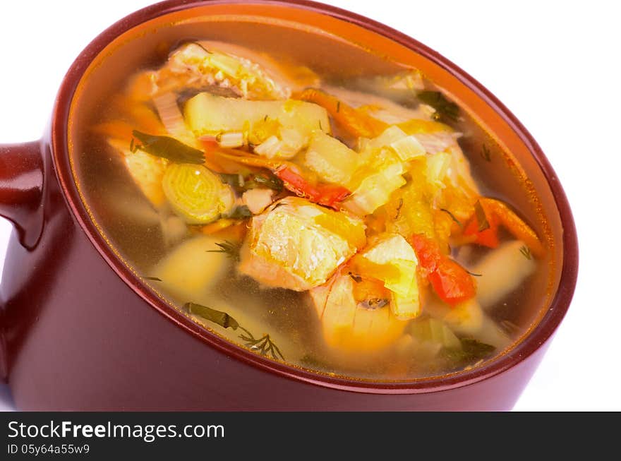 Tasty Homemade Fish Soup with Salmon, Potato, Leek, Carrot and Greens in Brown Soup Cup closeup on white background