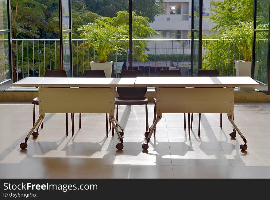 Desks on sunshine near window of classroom