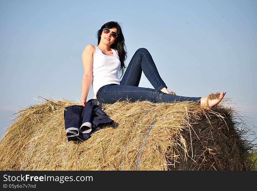 Beautiful girl sit on haystacks