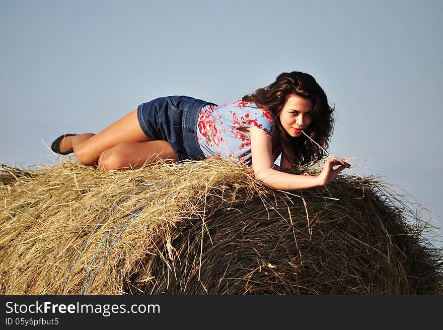 Beautiful girl sit on haystacks