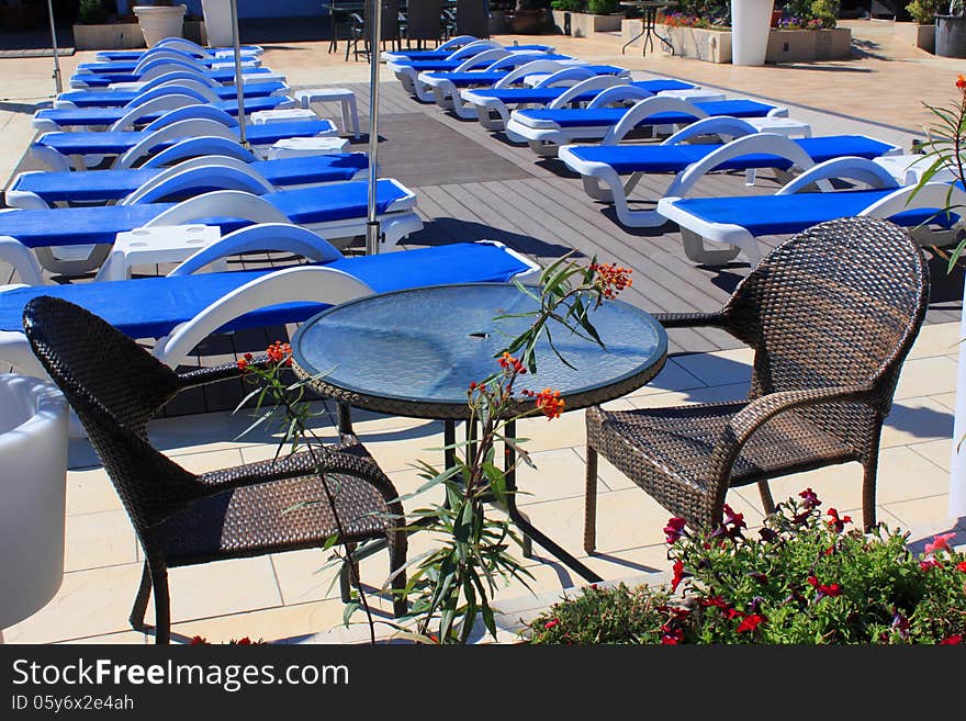 Sunny outdoor sunbeds and patio furniture with decorative flower in front