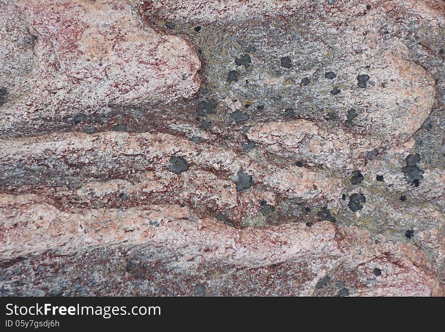 Surface of natural dark red stone (crimson quartzite porphyry) with black spots as background. Surface of natural dark red stone (crimson quartzite porphyry) with black spots as background