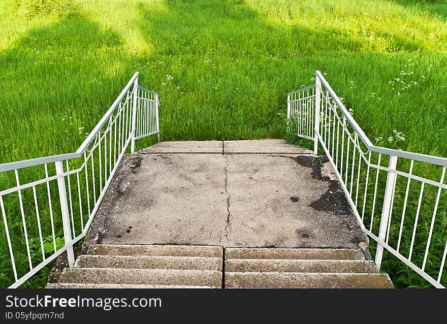 Old concrete staircase descends into the fresh grass. Old concrete staircase descends into the fresh grass