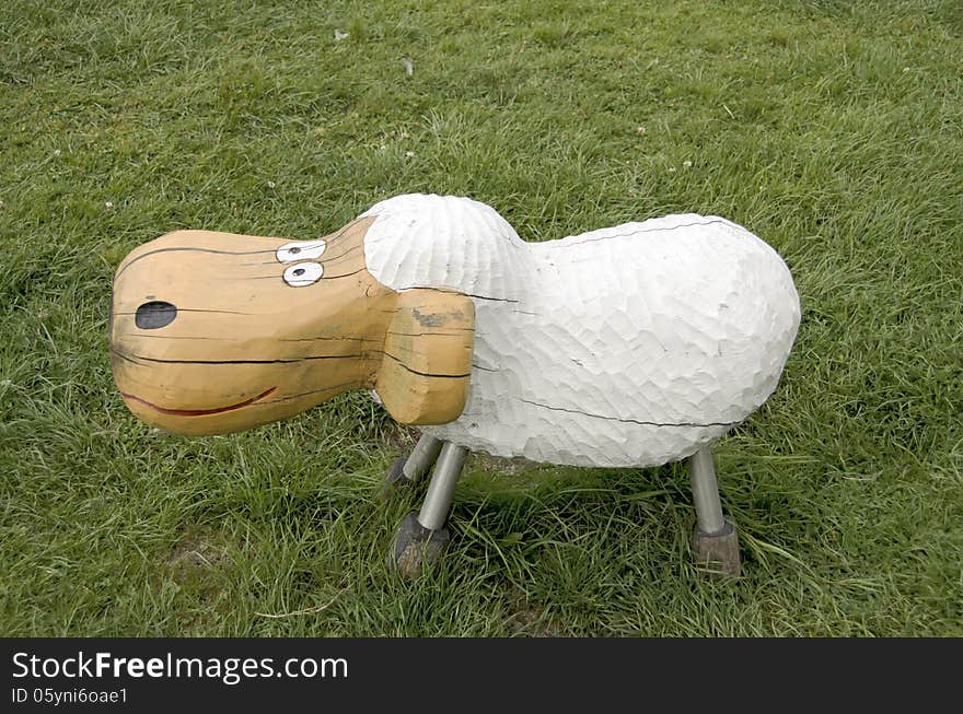 Sheep of wood, on a grass in a park playground.