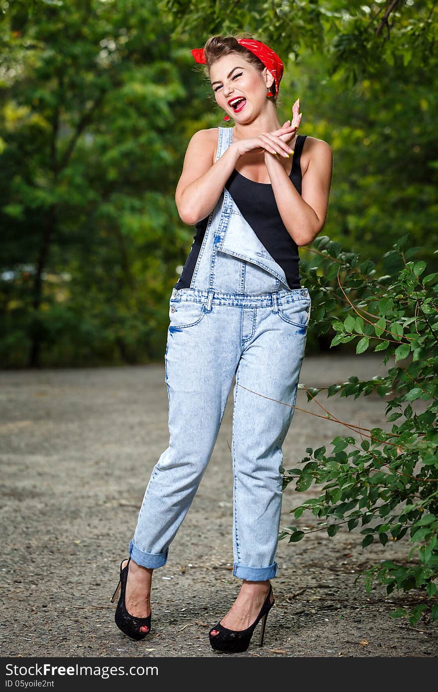 Beautiful pin-up girl in denim overalls and a T-shirt outdoors