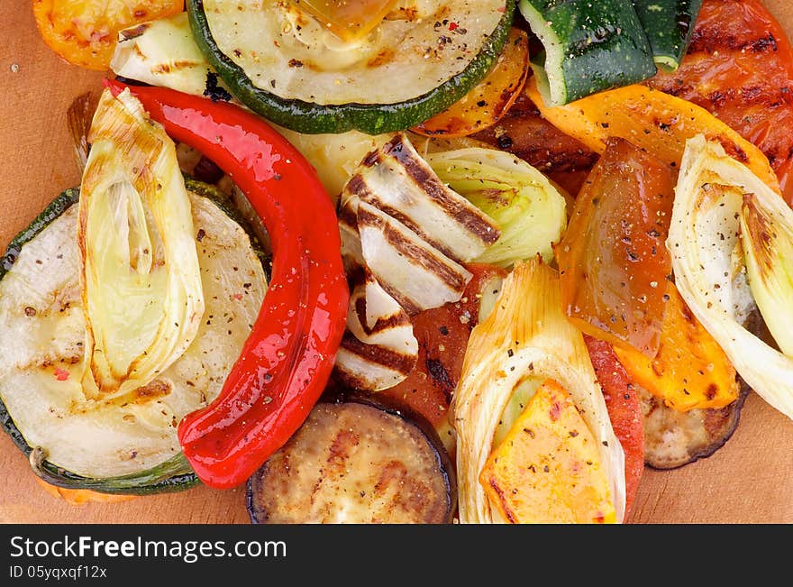 Various Grilled Vegetables with Chili Pepper and Spices closeup on Wooden Cutting Board. Top View