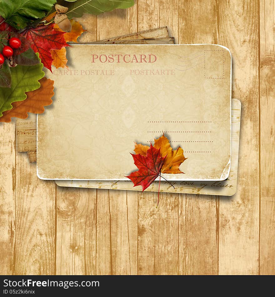 Autumn leaves over wooden background with postcard