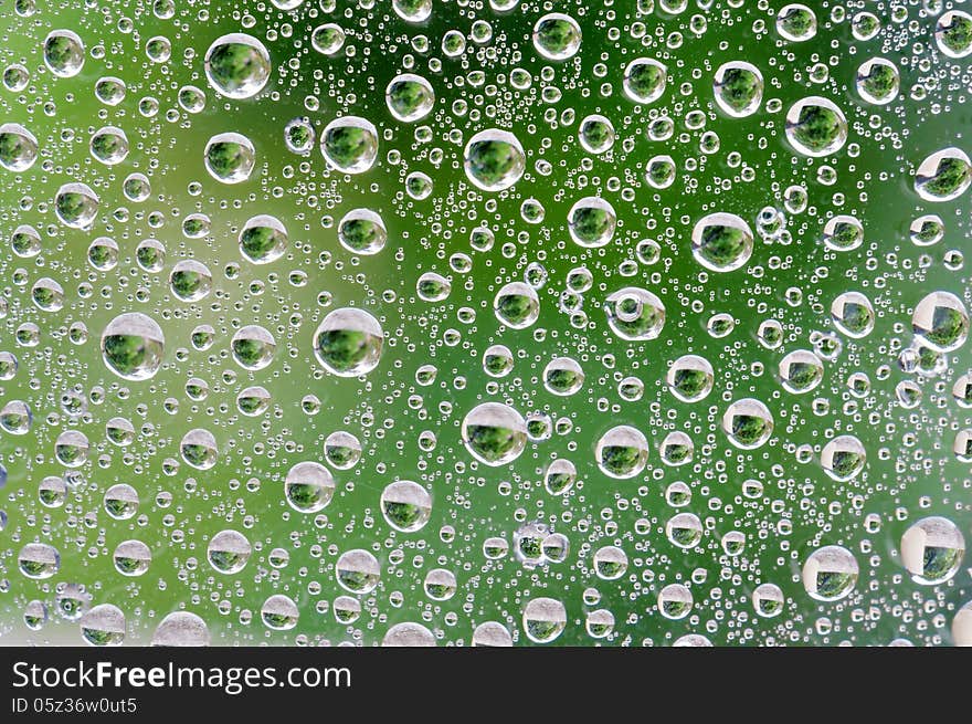 Water Drops on window with green background.