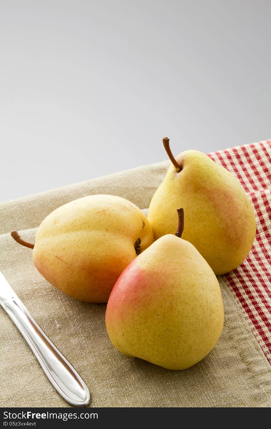 Three ripe pears on a linen napkin on a gray background