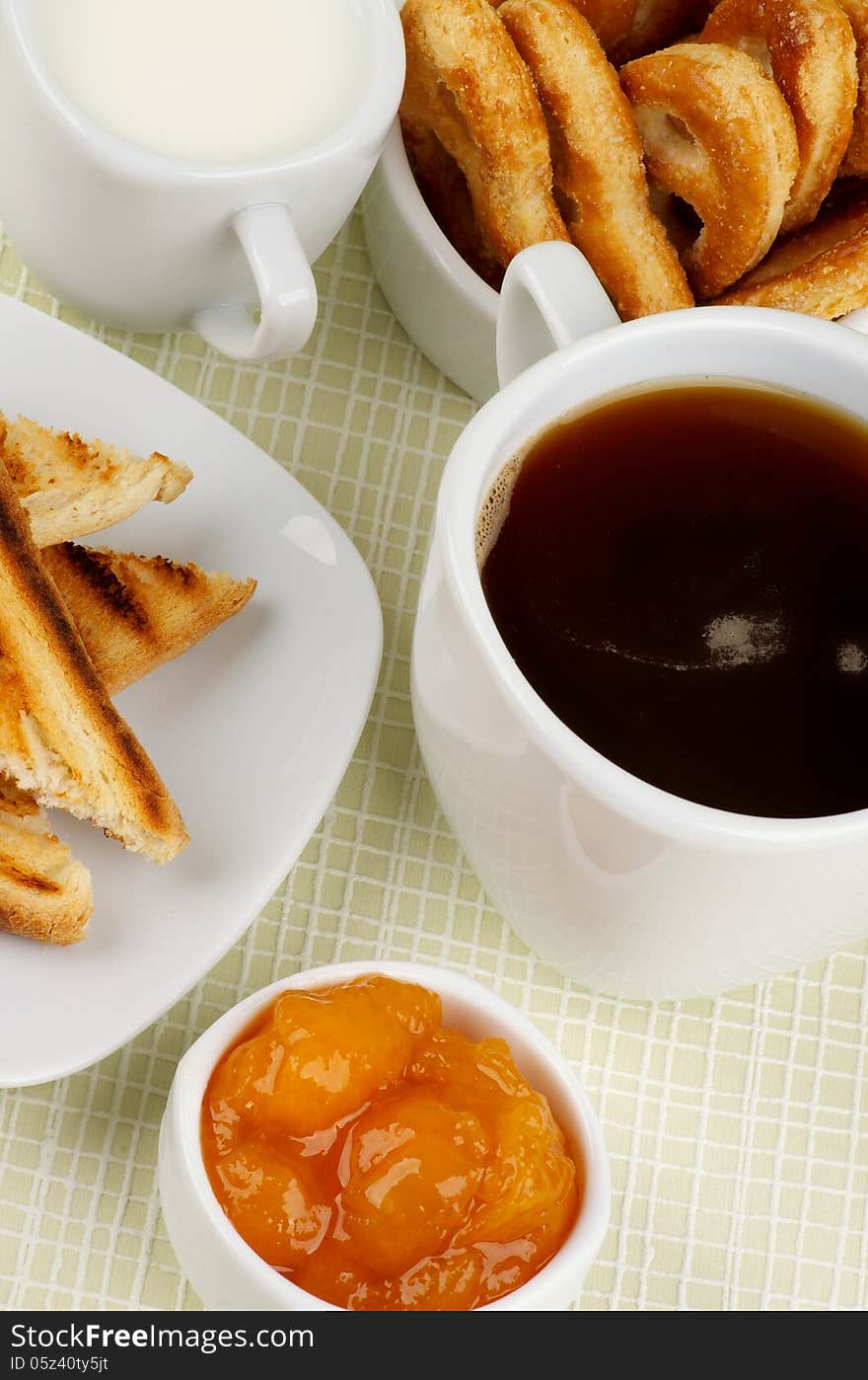 Coffee Break with Milk, Toasts, Apricot Jam and Puff Pastry closeup on Checkered background