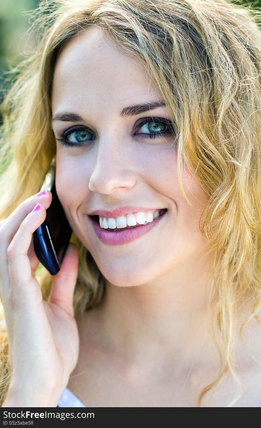 Young blonde girl whit smartphone at the park