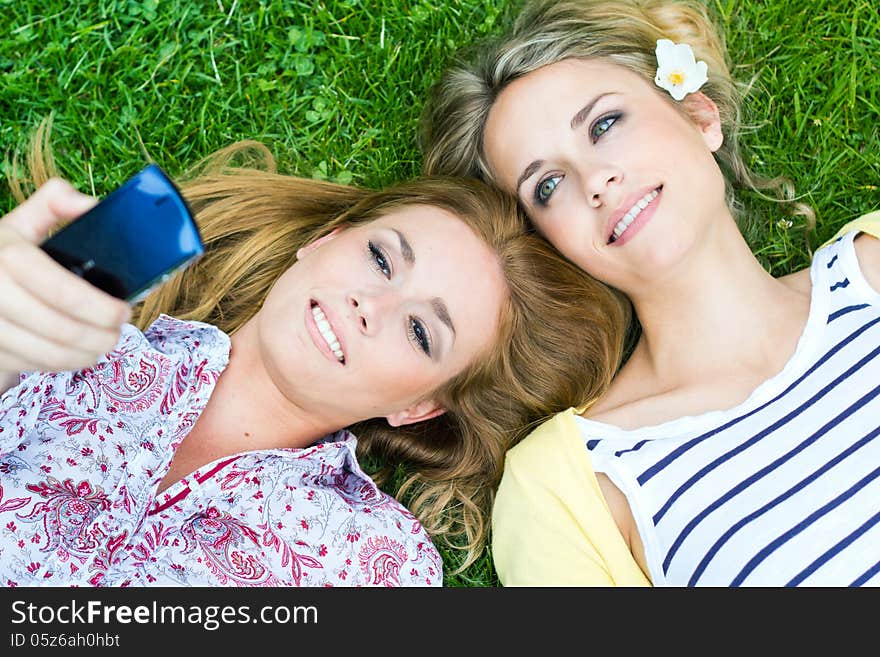 Portrait of two sisters with smartphone at the park