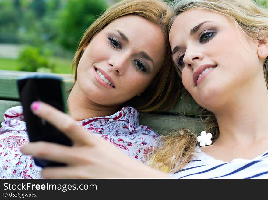 Portrait of two sisters with smartphone at the park