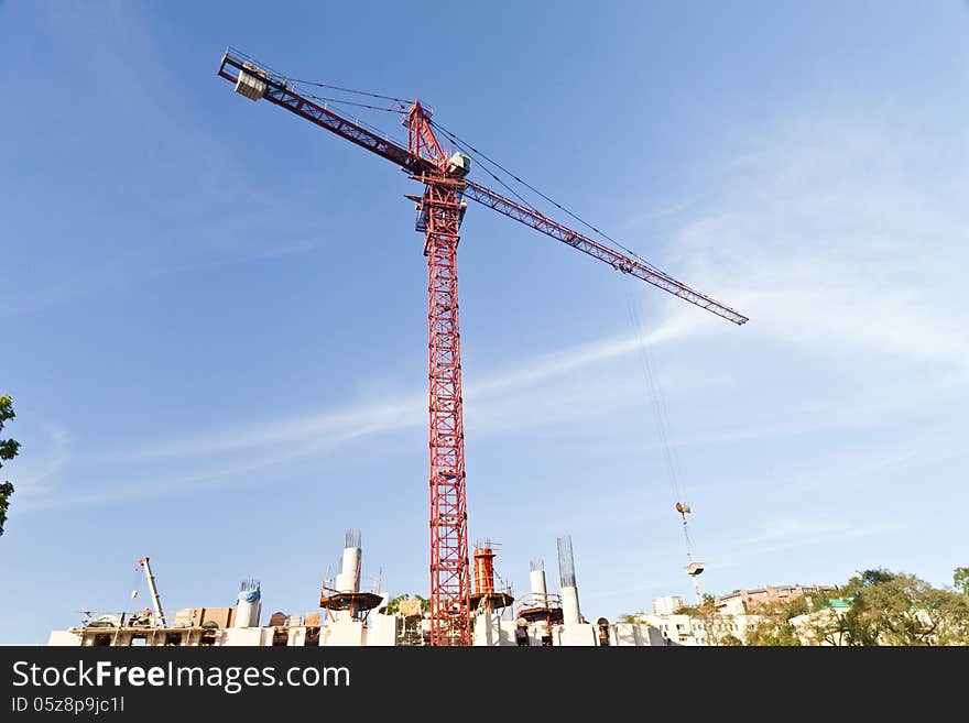 The lifting crane works at building in beams of the coming sun