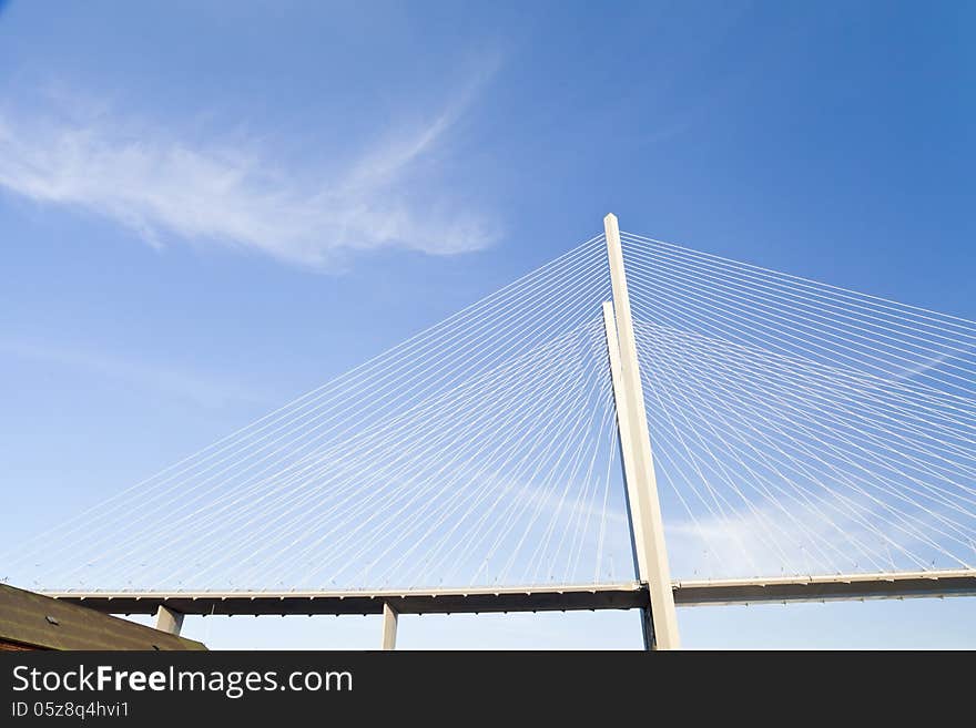 Big suspension bridge in beams of the coming sun against the blue sky