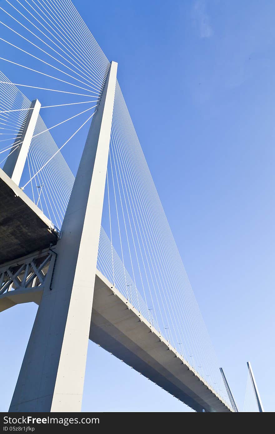 Big suspension bridge in beams of the coming sun against the blue sky