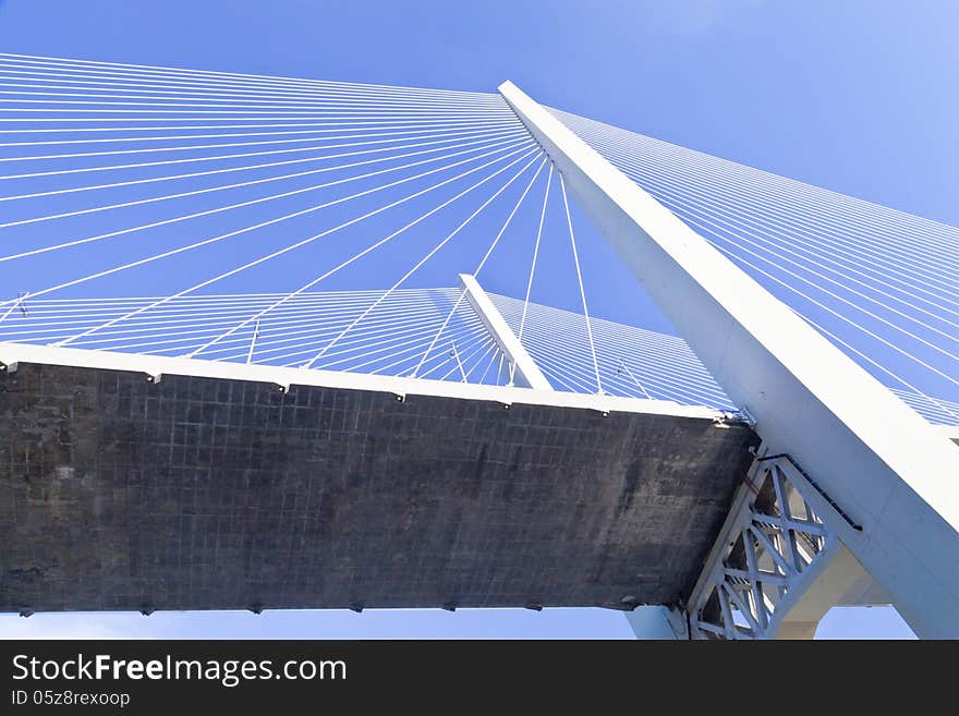 Big suspension bridge in beams of the coming sun against the blue sky