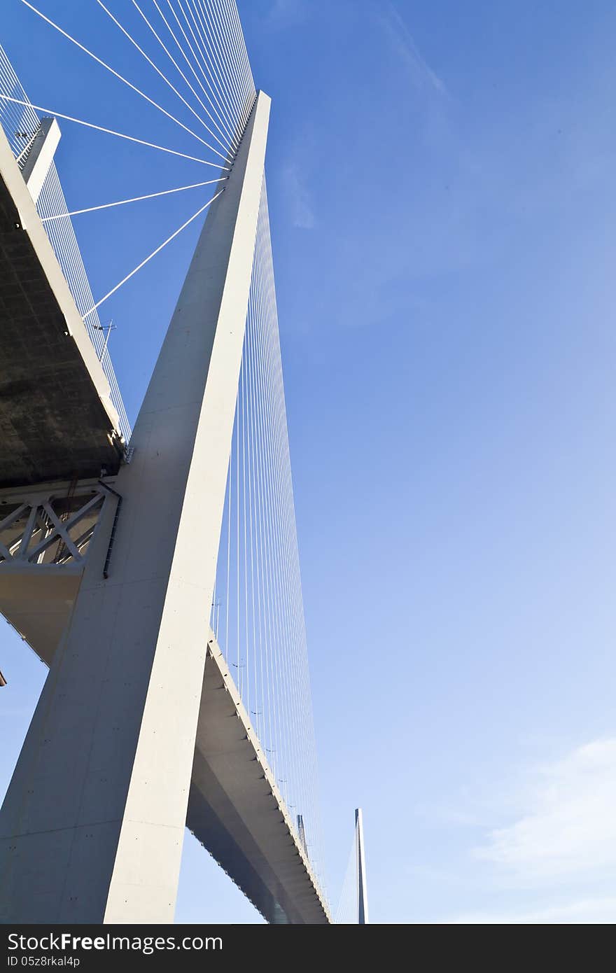 Big suspension bridge in beams of the coming sun against the blue sky