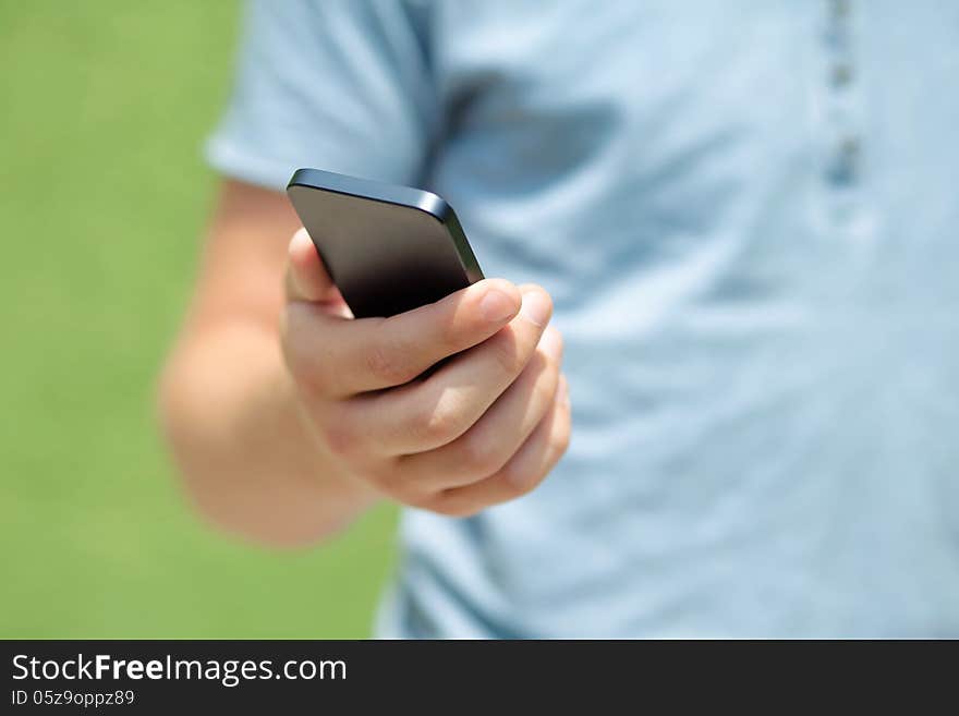 Boy holding a phone against a green wall