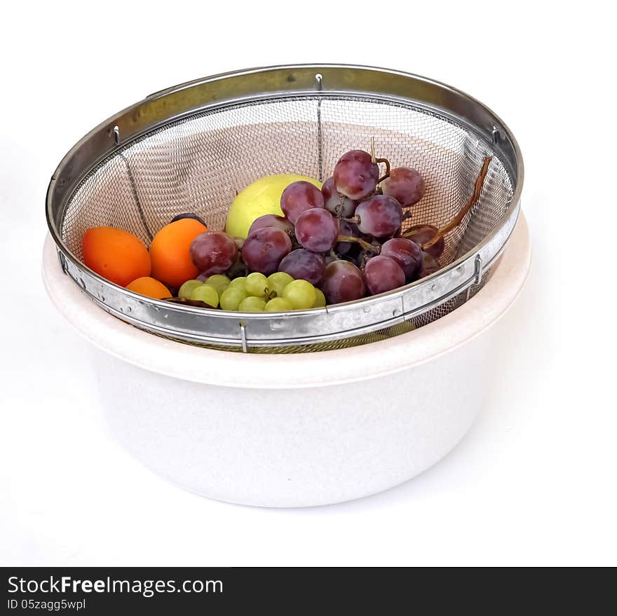 Summer fruits of grapes, apricots and apples in a strainer within a white bucket. Summer fruits of grapes, apricots and apples in a strainer within a white bucket