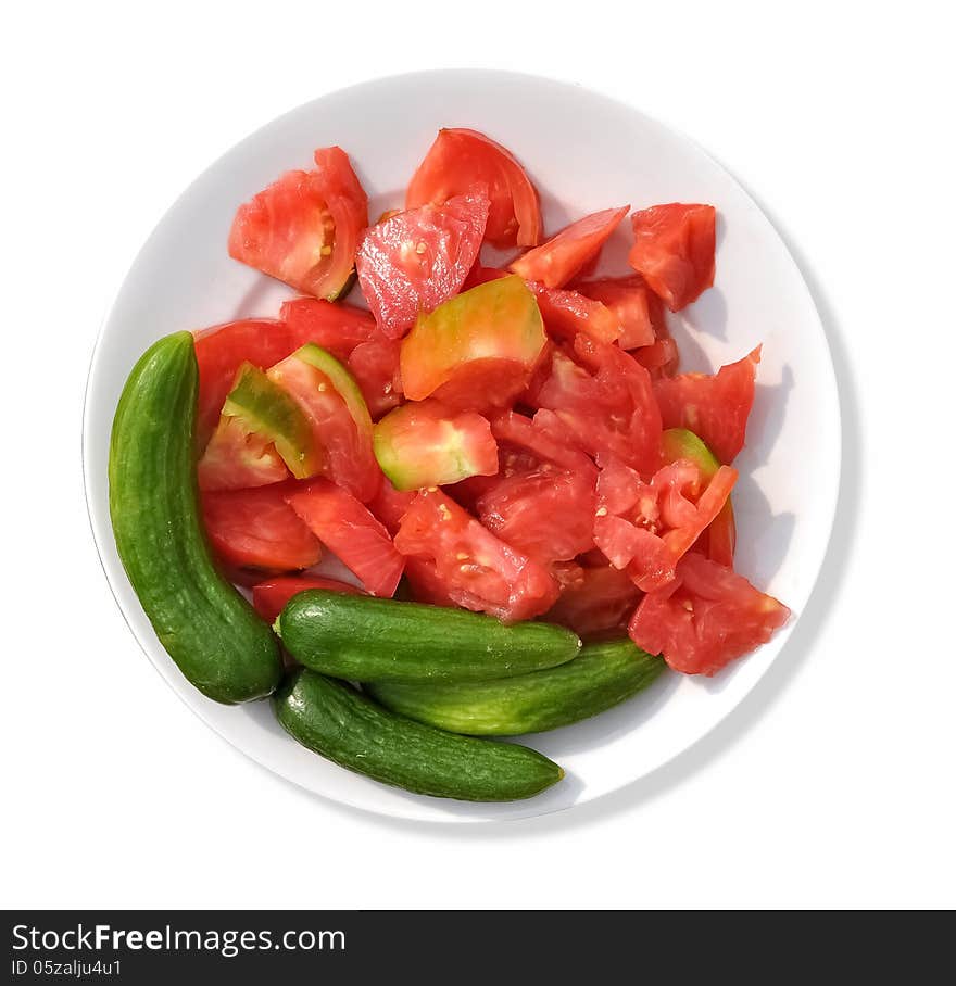 A circular white plate that contains sliced tomatoes with green cucumbers. A circular white plate that contains sliced tomatoes with green cucumbers