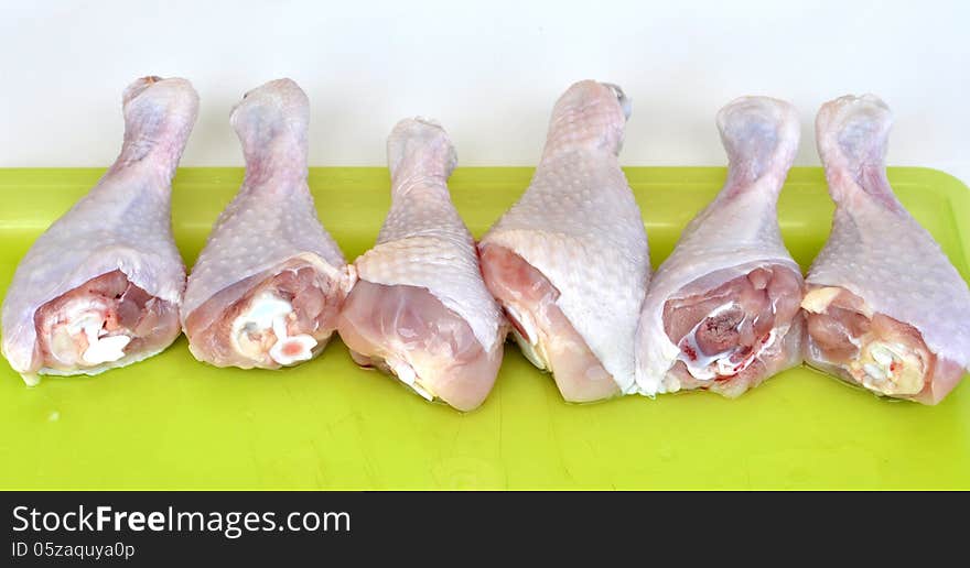 Cleaned chicken legs on a yellow plastic tray lined up horizontally. Cleaned chicken legs on a yellow plastic tray lined up horizontally