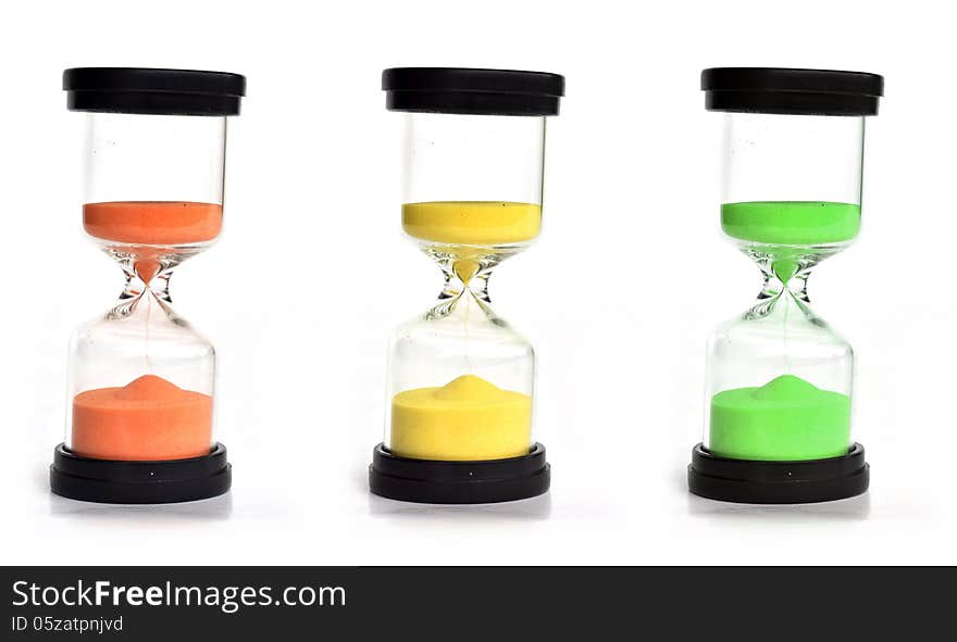 Three colored sand clocks of orange, yellow and green