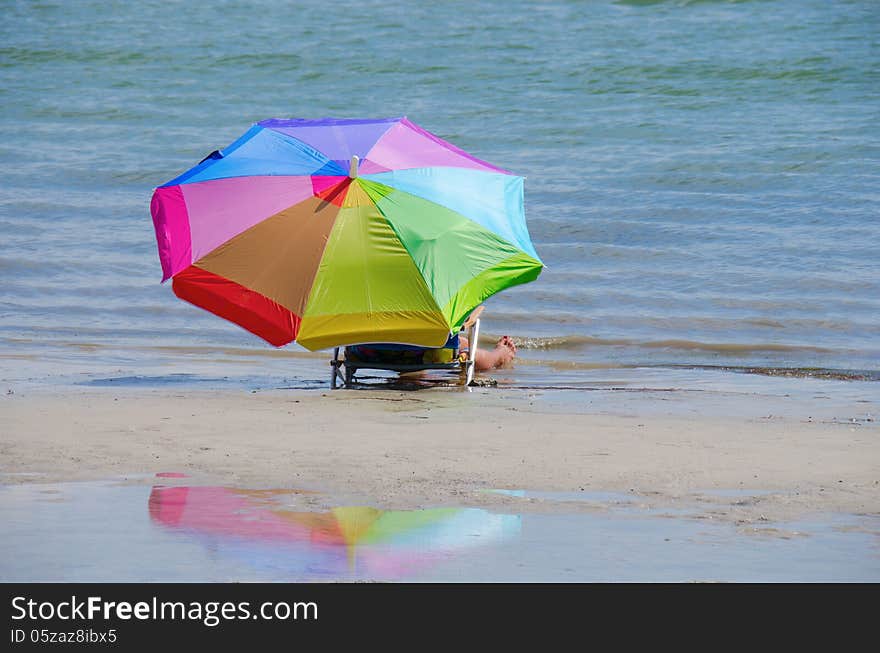 Woman and colorful umbrella by the shoreline