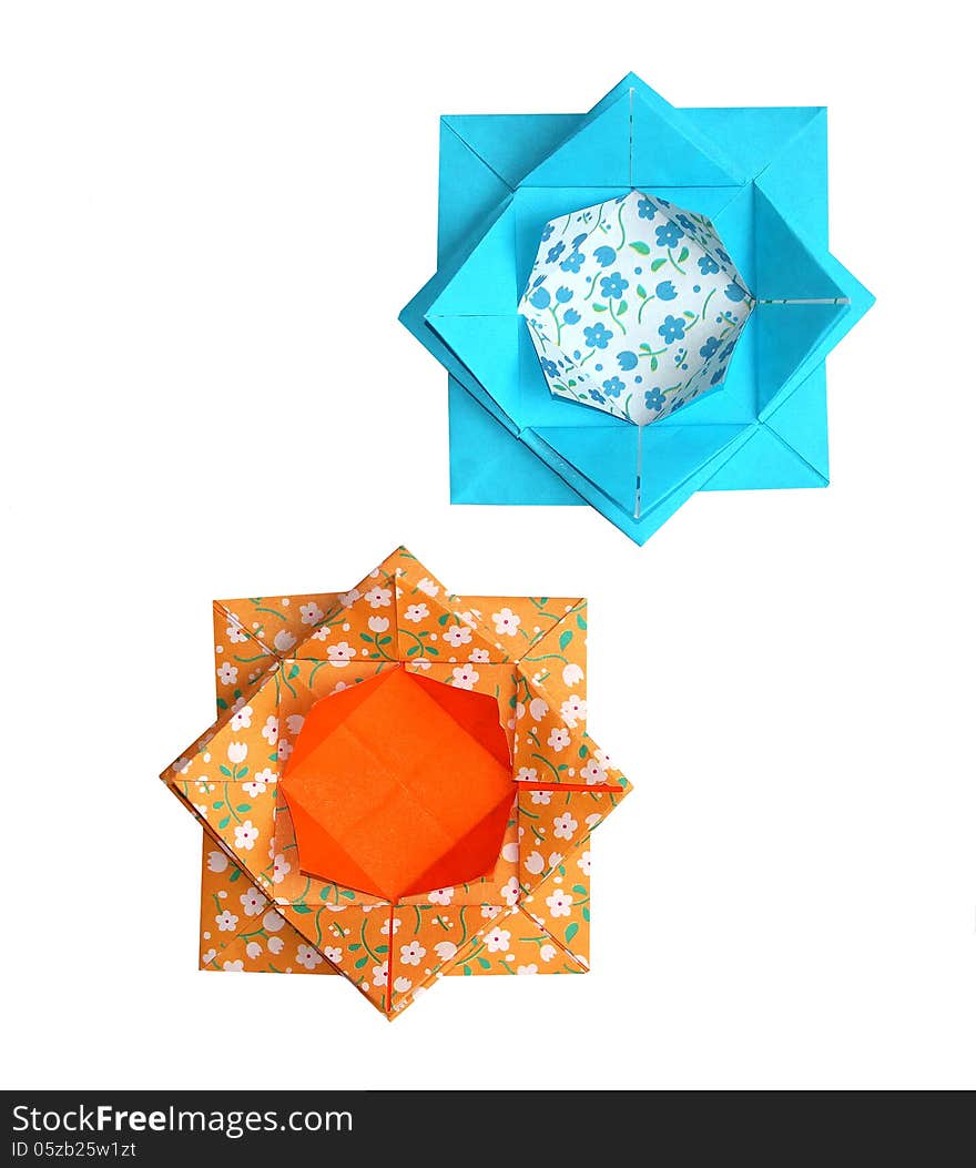 A pair of origami lotus flowers in turquoise and orange made from traditional paper with a floral pattern. A pair of origami lotus flowers in turquoise and orange made from traditional paper with a floral pattern.