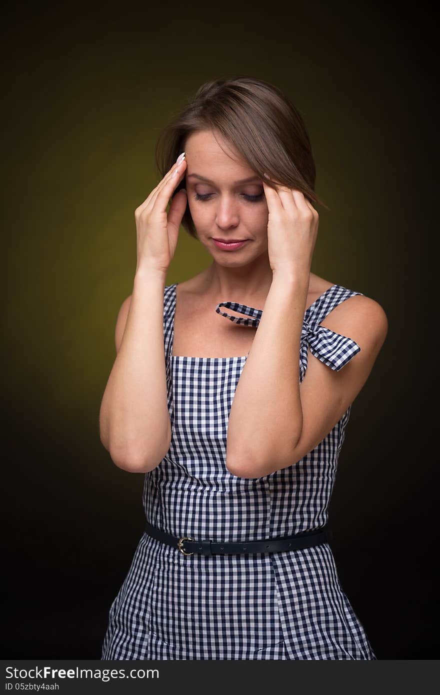 Beautiful woman with headache on golden-dark background