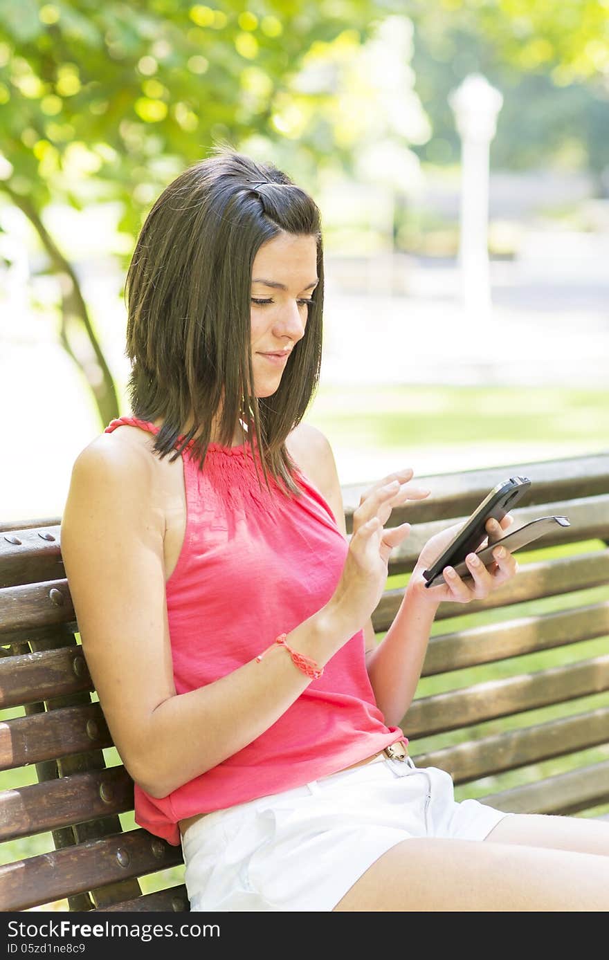 Beautiful girl using phone in the park. Beautiful girl using phone in the park.