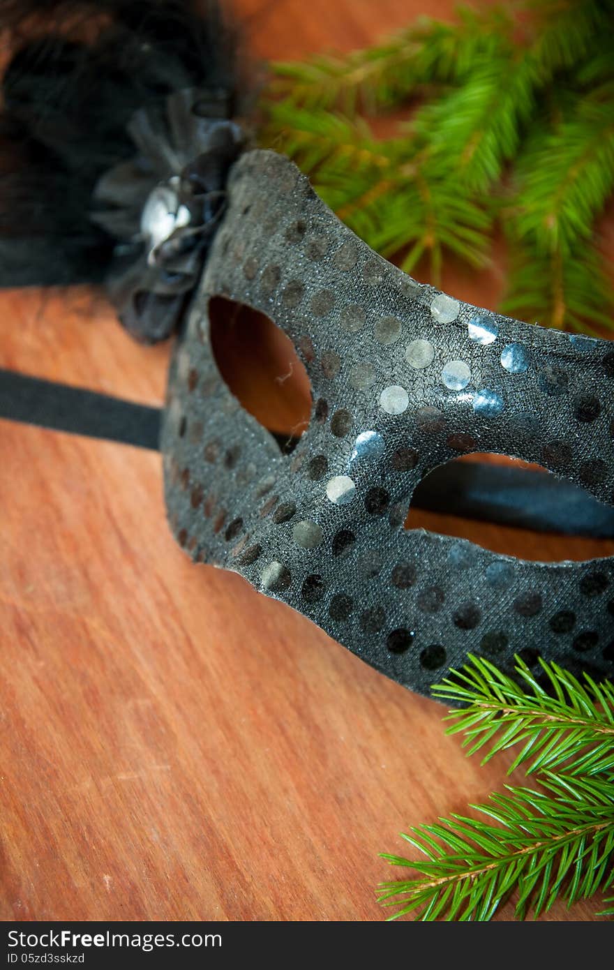 Spruce branches and carnival mask on a wooden table