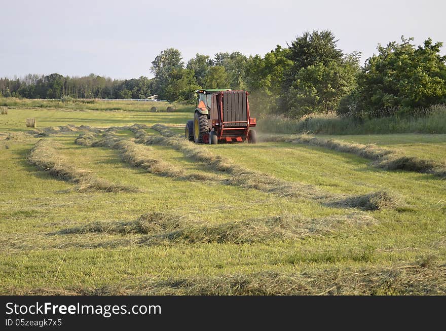 Harvesting a fresh cut field of hay in rural Michigan, USA. Harvesting a fresh cut field of hay in rural Michigan, USA