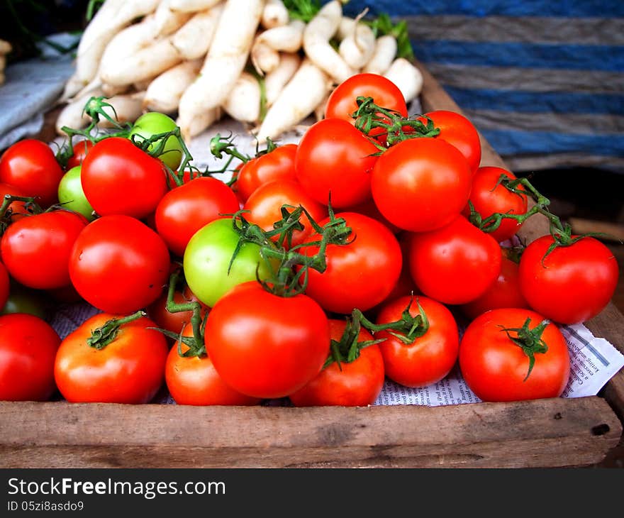 Tomatoes fruits for sale with head lettuce on the background.