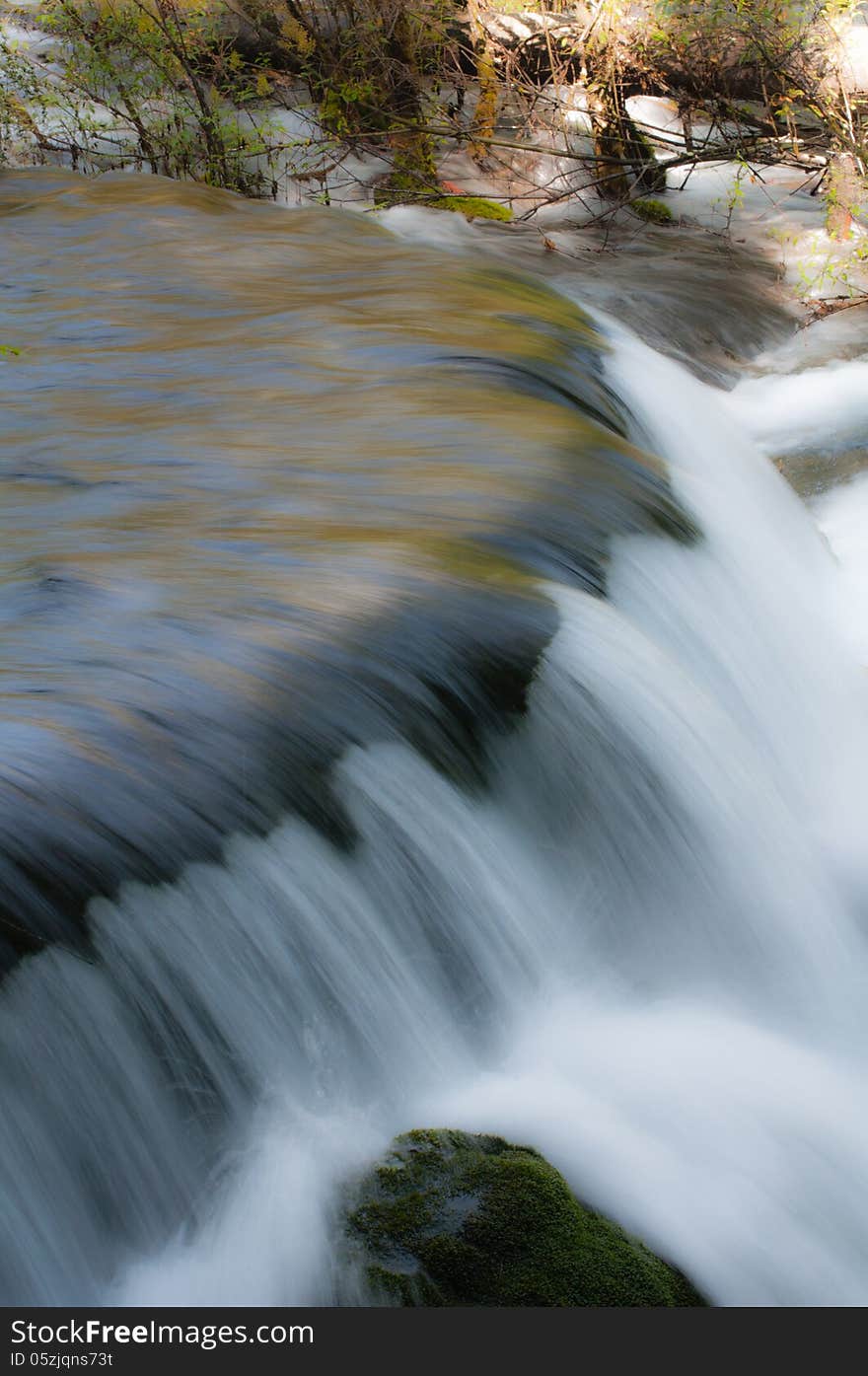 Waterfall in woods ,splashing on stone