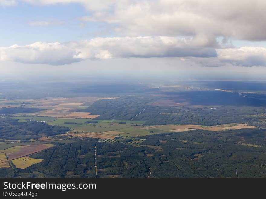 Blue sky and puffy clouds on height of 2000 m above Latvia. The Fields and forests are in the sunny light. Blue sky and puffy clouds on height of 2000 m above Latvia. The Fields and forests are in the sunny light.