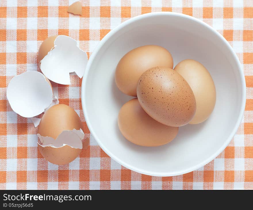 Bowl with white and yellow eggs on tablecloth background