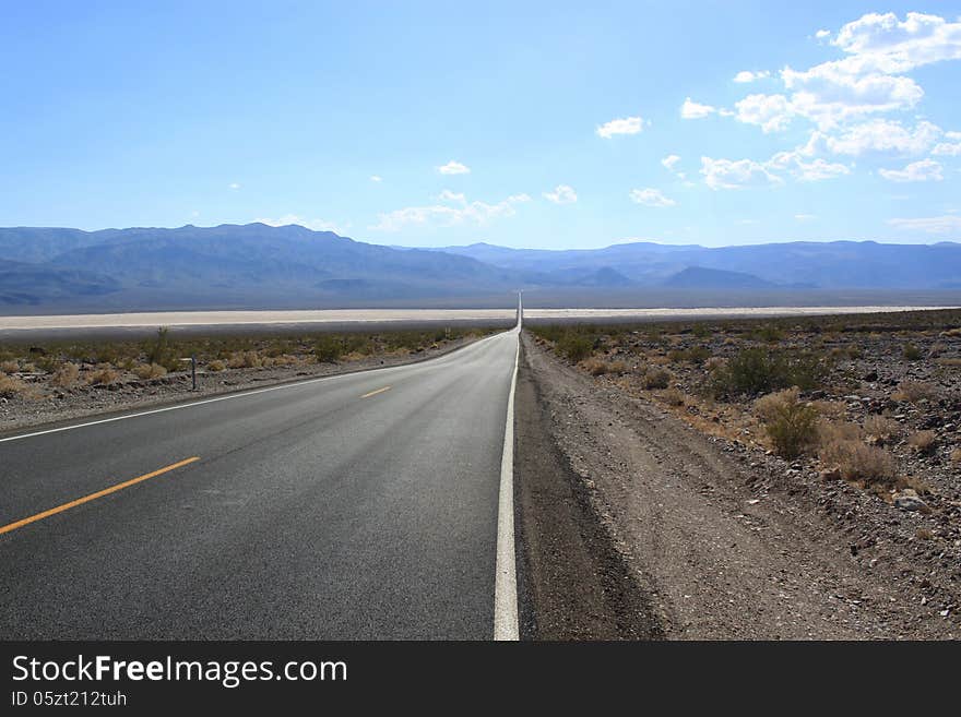 Straight asphalt road through the desert, California, USA