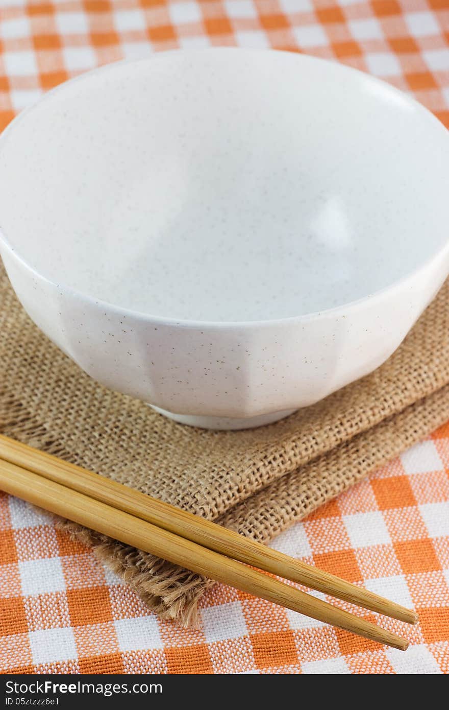 Two chopsticks next to a yellow and white bowl. Two chopsticks next to a yellow and white bowl