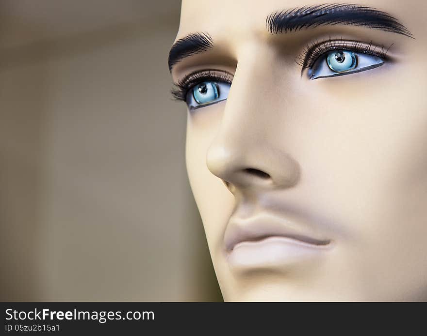 Close up of the face of a male mannequin with deep blue eyes.