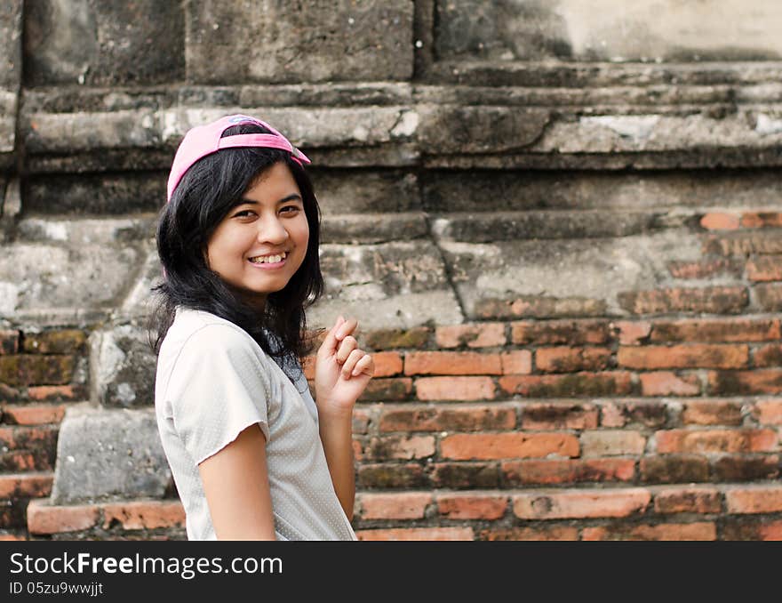 Pretty girl posing and smiling while standing near brick wall background. Pretty girl posing and smiling while standing near brick wall background